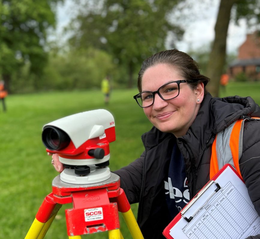 Female surveyor with some measuring equipment smiling at the camera